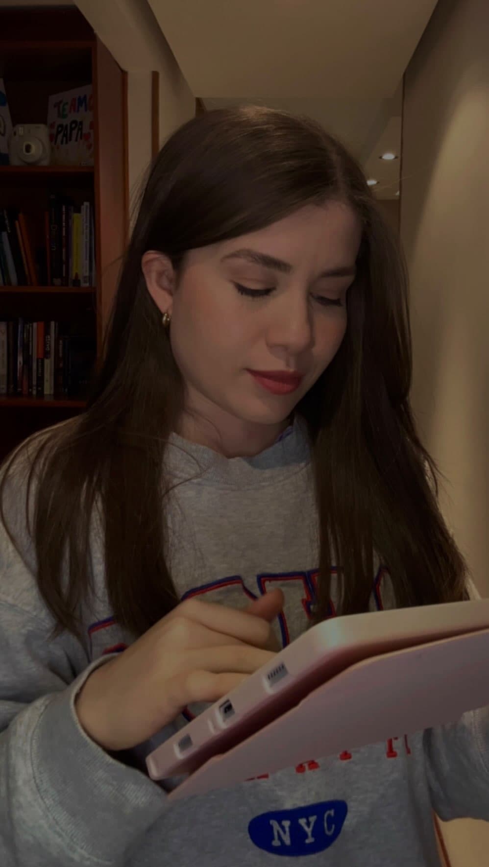 Francis leyendo con sudadera NYC en su biblioteca