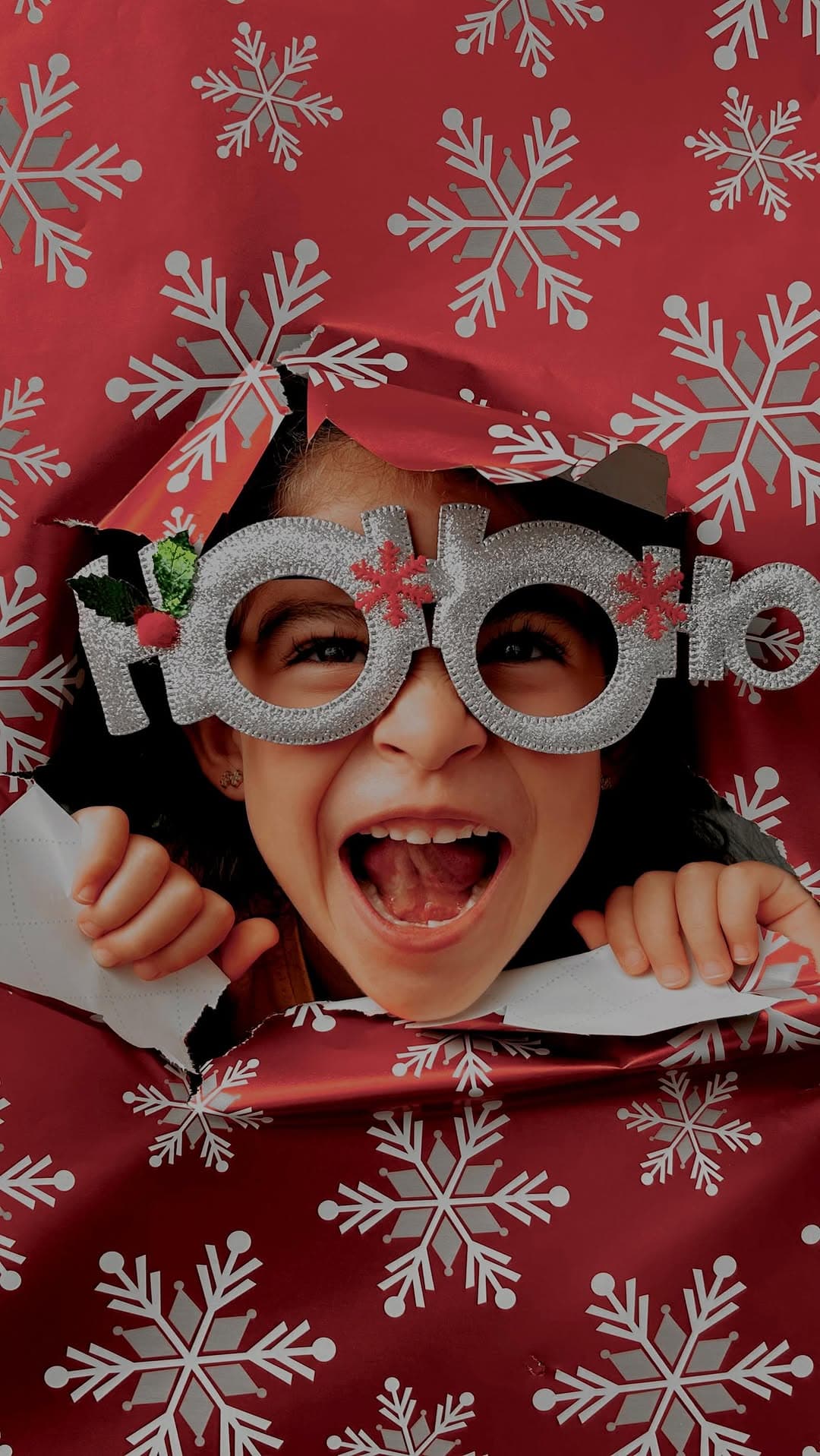 Hija de Francis asomándose por papel de regalo navideño con lentes HoHoHo